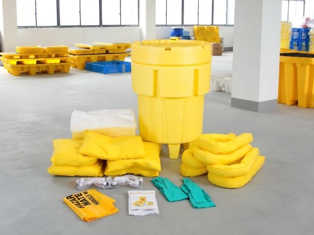 Spill kit contents laid out including absorbent pads, socks, pillows, gloves, goggles, disposal bags and instruction sheet